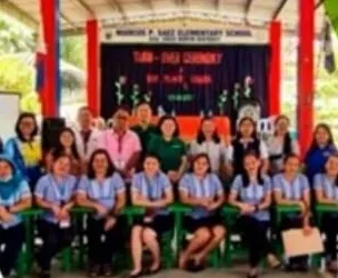 Teachers of Marcos P. Saez Elementary School seated on new green chairs at the turnover ceremony