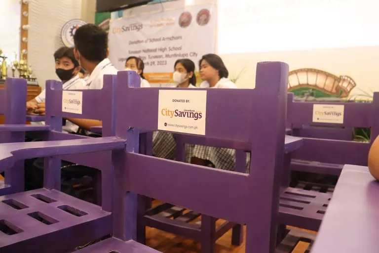 Purple recycled-plastic armchairs labelled ‘Donated by CitySavings’ with students seated behind them