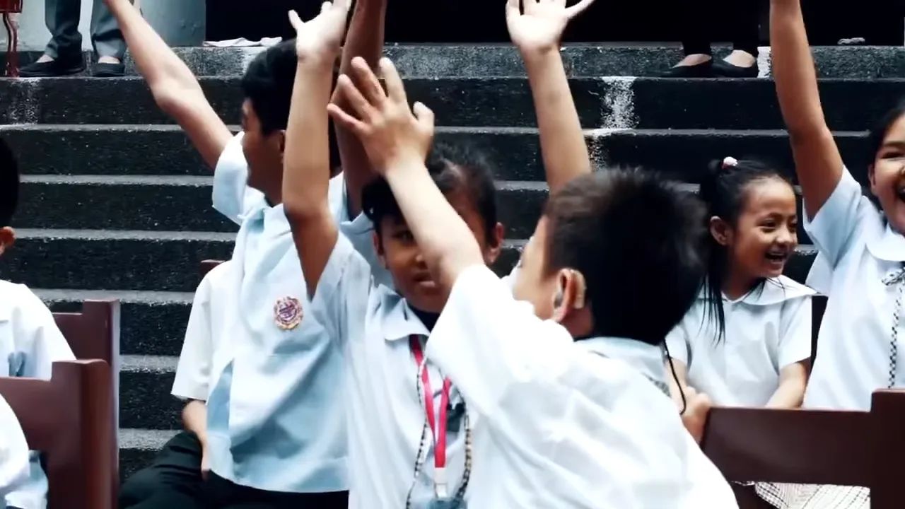 Smiling students raising their hands while seated on their new brown school chairs